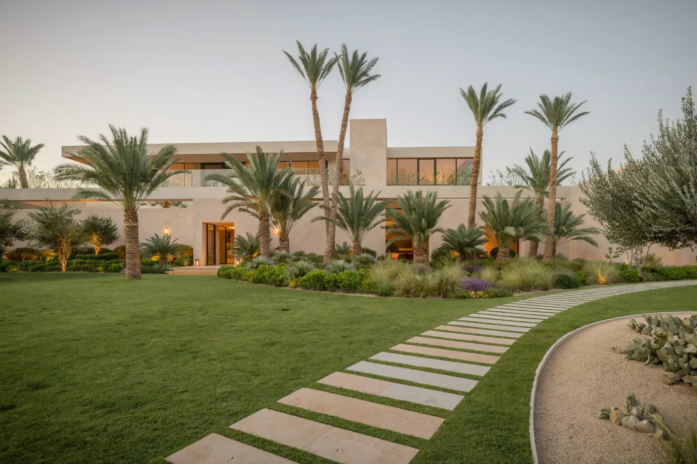 Landscaped villa garden at golden hour with lawn, palms and stone pathway